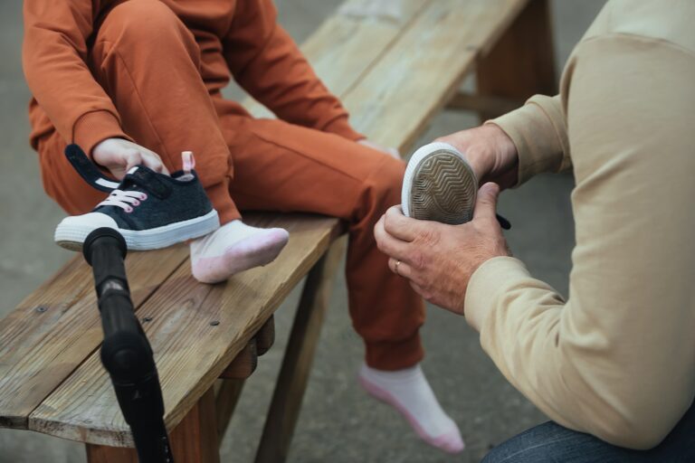 dad-dressing-his-little-daughter-shoes-in-the-park-2026-03-17-20-09-59-utc (1)